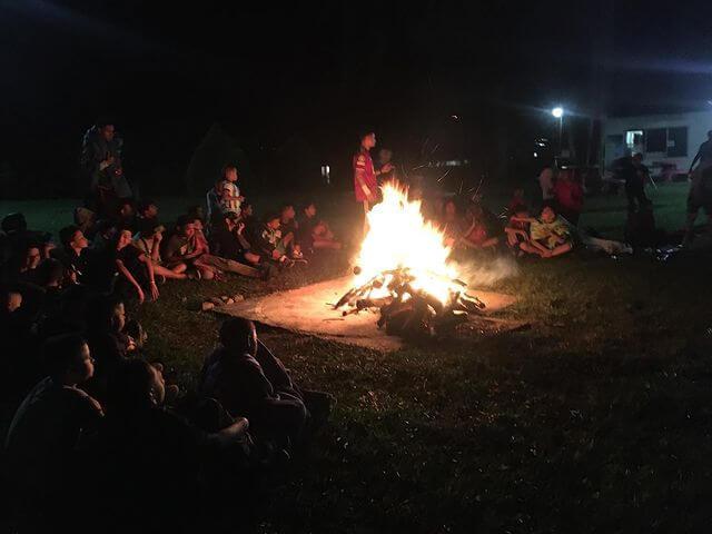 Fogata con muchos niños alrededor en un campamento.