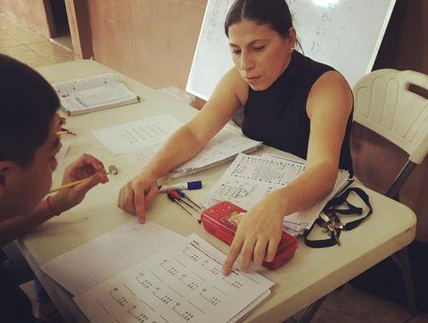 Tutora señala con el dedo en un cuaderno para enseñar a niño.