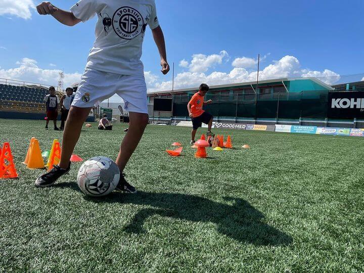 Jovenes en practica de futbol con conos.