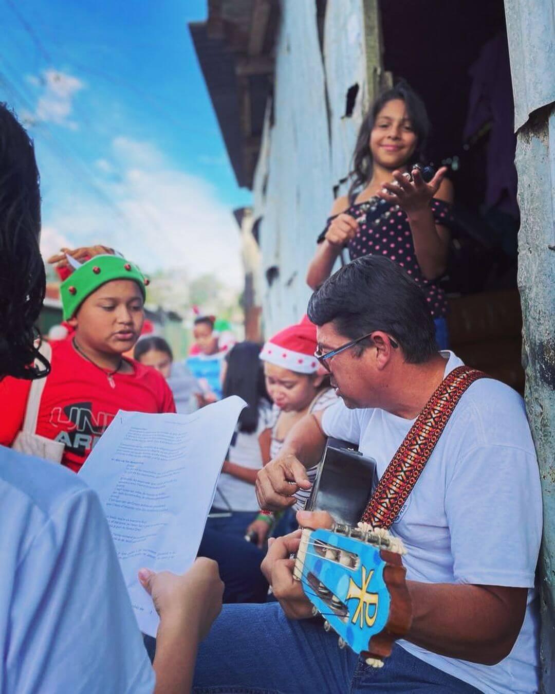 People singing Christmas songs with a guitar.